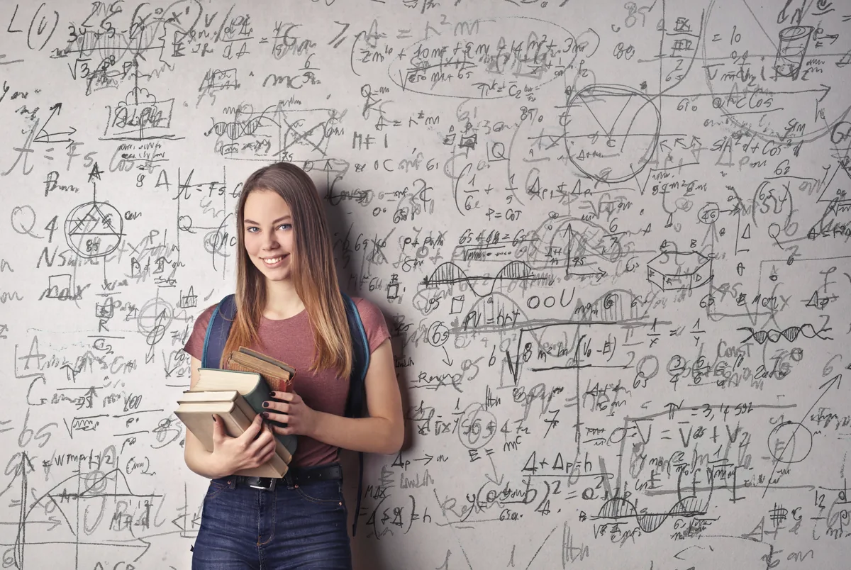 Studentessa con libri davanti a una lavagna